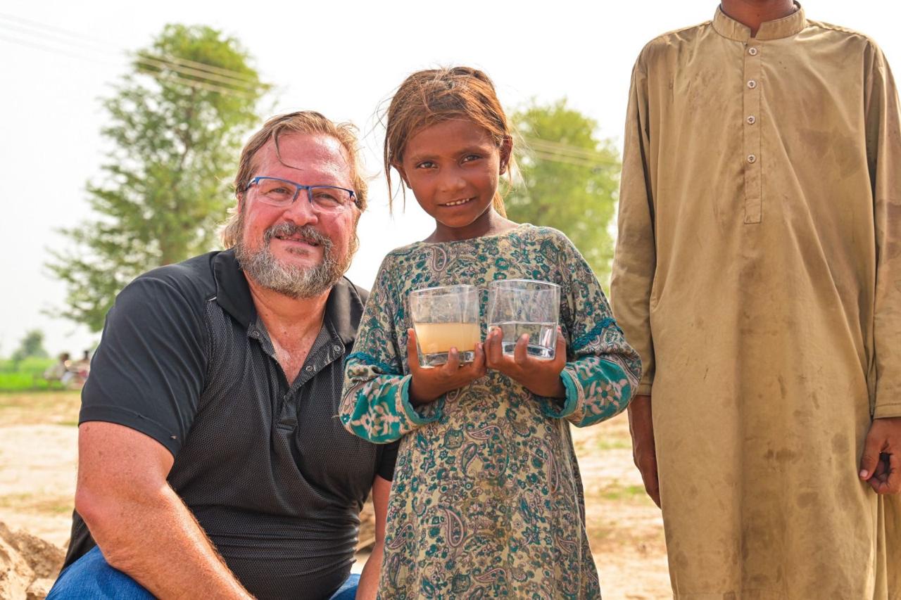 Kevin Eichhorn with a child holding clean and dirty water — Clean Water Life mission
